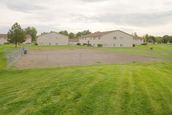 View of the fenced in dog park with Olympic Village Apartments in the background.